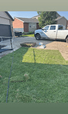 Fresh sod laid across a front yard with rolls stacked near the driveway